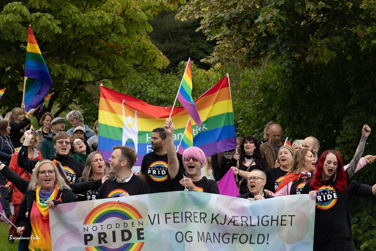 Fra paraden til Notodden Pride. Jublende menesker med regnbueflagg